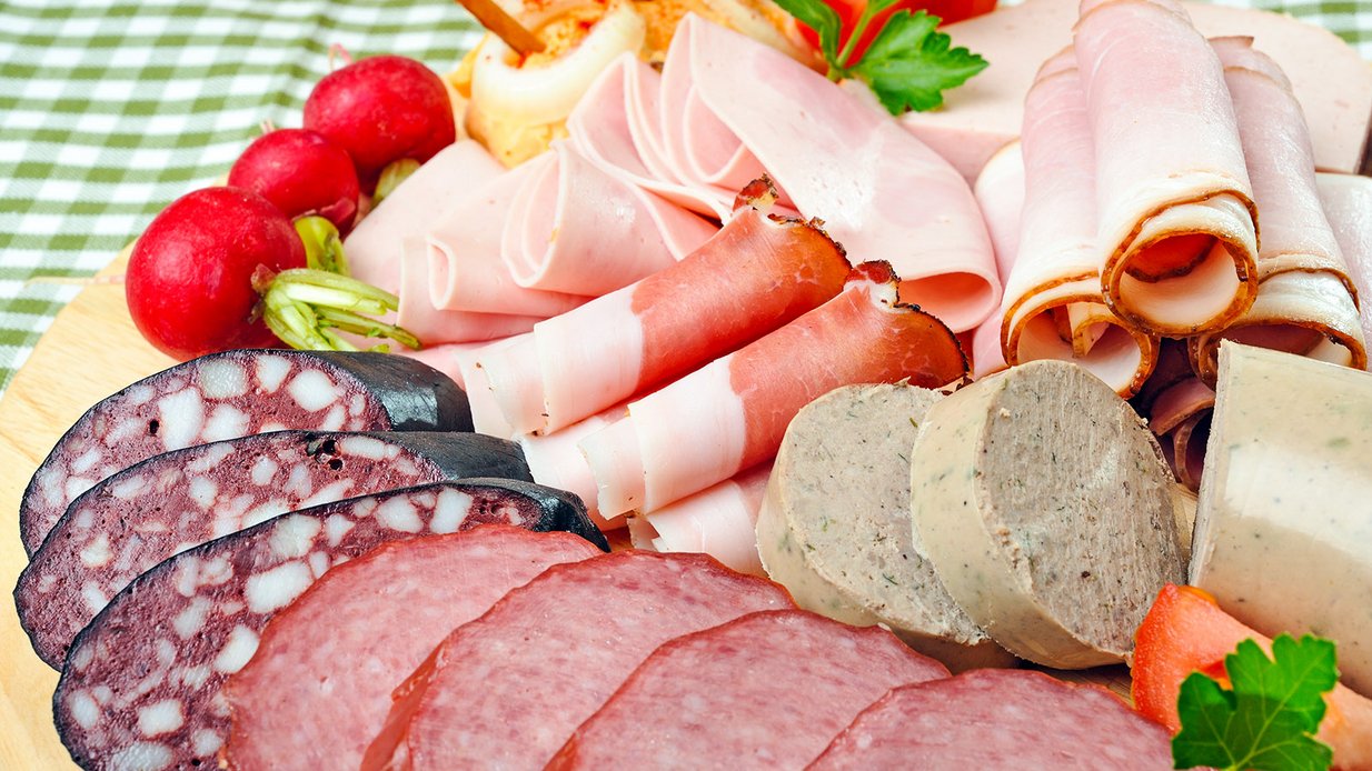 Angerichtete Wurst- und Fleischplatte mit Gemüse und Kräutergarnitur.